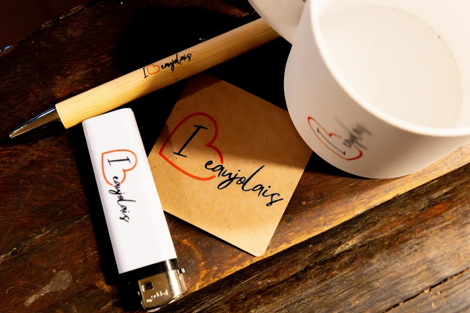 objets personnalisés au nom de la marque I Love Beaujolais : un stylo en bambou, un mug blanc, un magnet en carton recyclé, un briquet blanc.